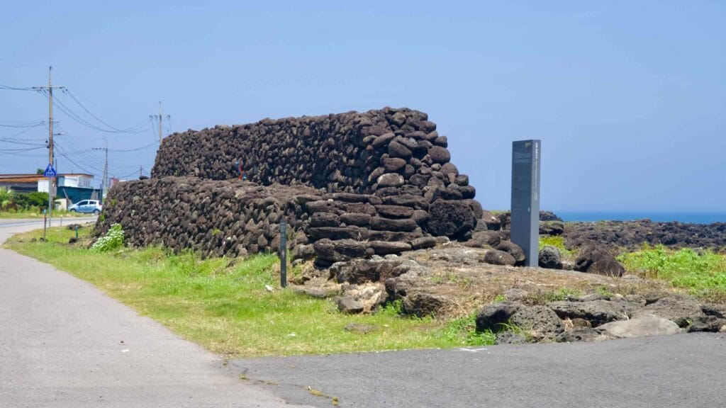 A section of the Onpyeong Hwanhaejangseong coastal wall stands above the basalt shore.