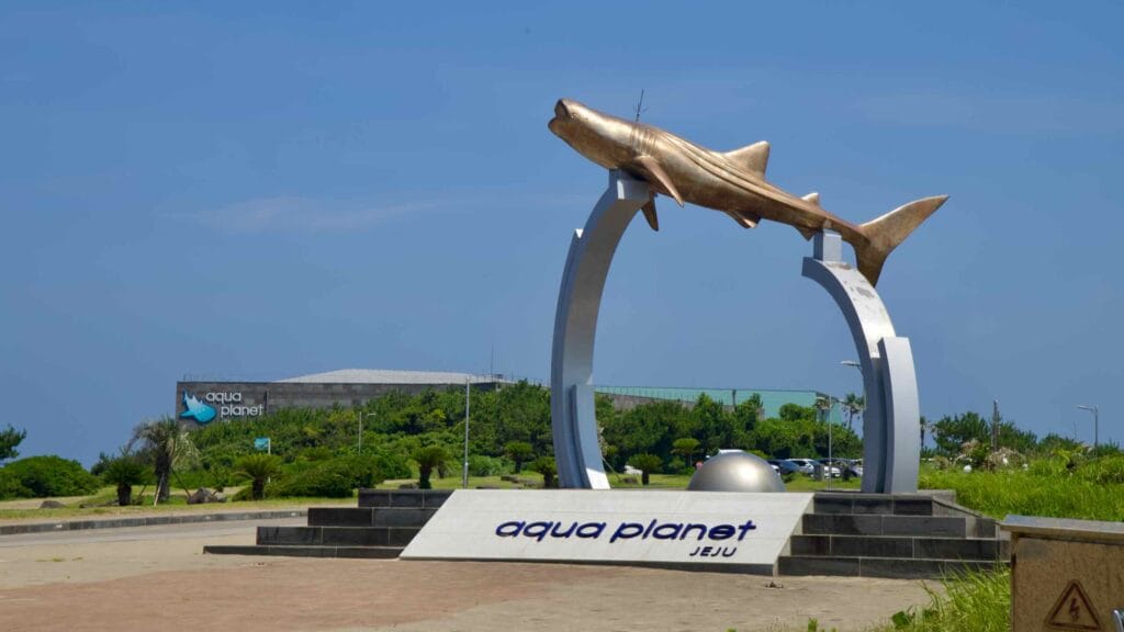 A whale shark statue arches over the Aqua Planet Jeju entrance.