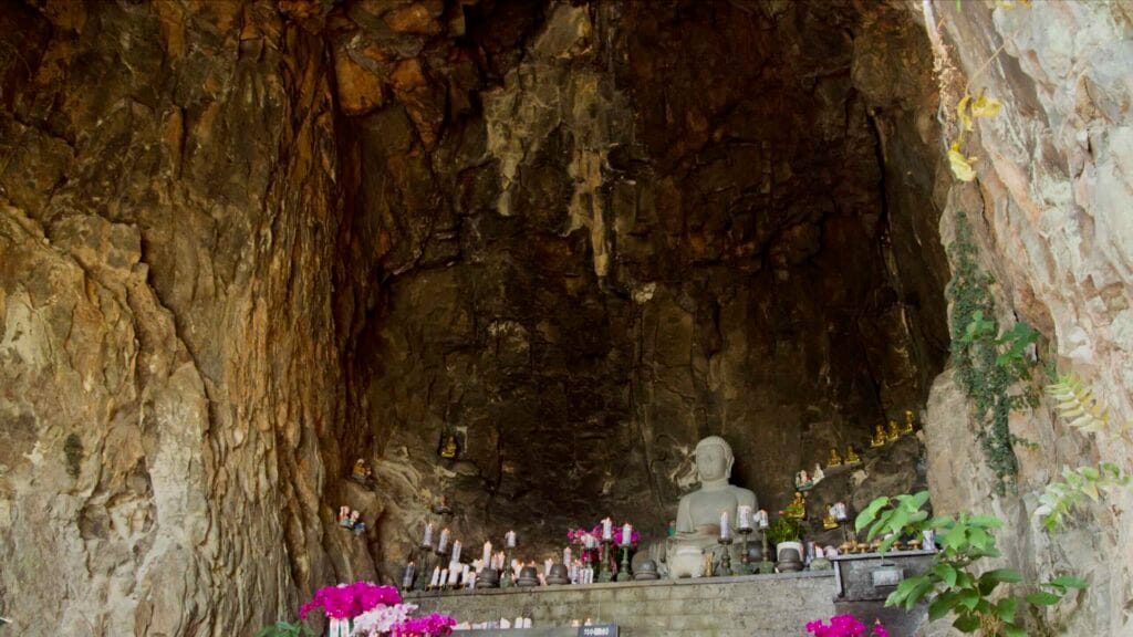 Closer view of the cave Buddha and orchids at Bomunsa, with votive candles and offerings.