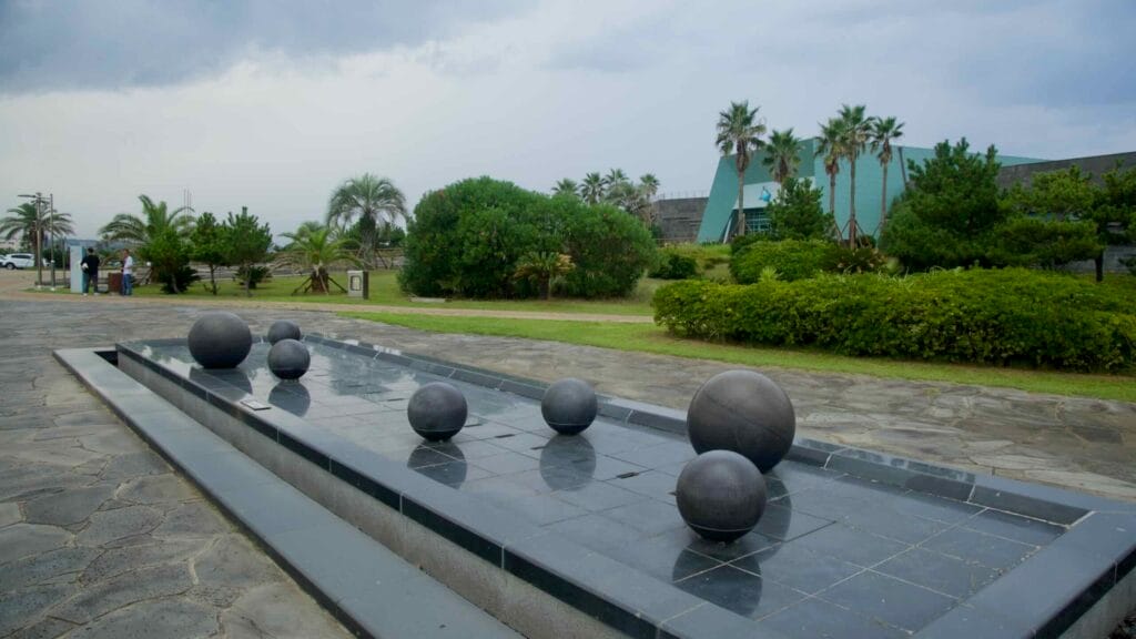 Spherical fountains dot a reflecting pool outside Aqua Planet Jeju.