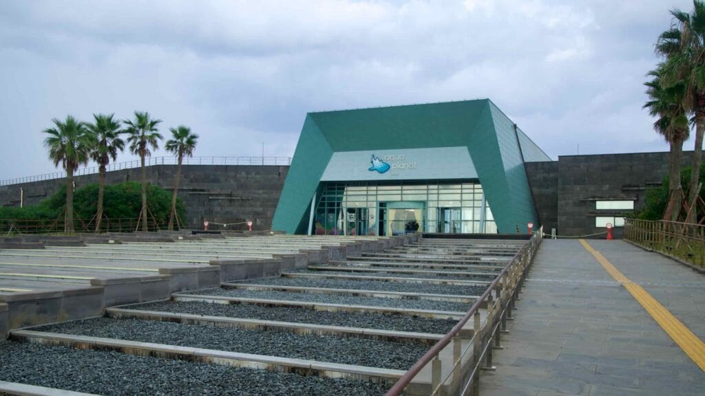 The angular entrance of Aqua Planet Jeju faces a wide stone forecourt.