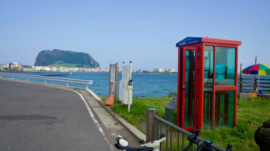 A red stamp booth sits on the waterfront with Sunrise Peak visible beyond.