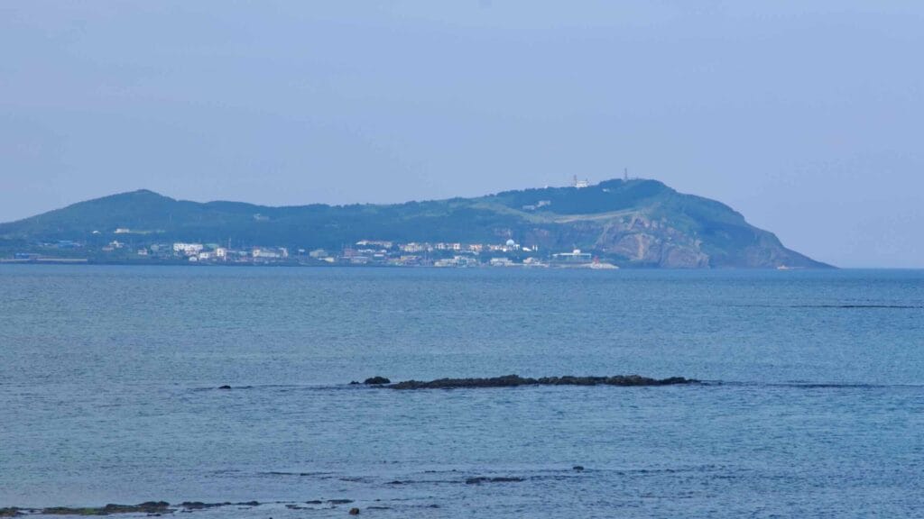 Udo Island spans the horizon with an orange lighthouse just off Dumun Port.