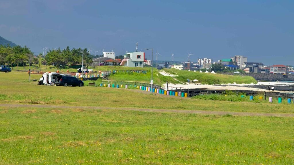 Grassy parkland overlooks the white sands at Gimnyeong Seongsegi Beach.
