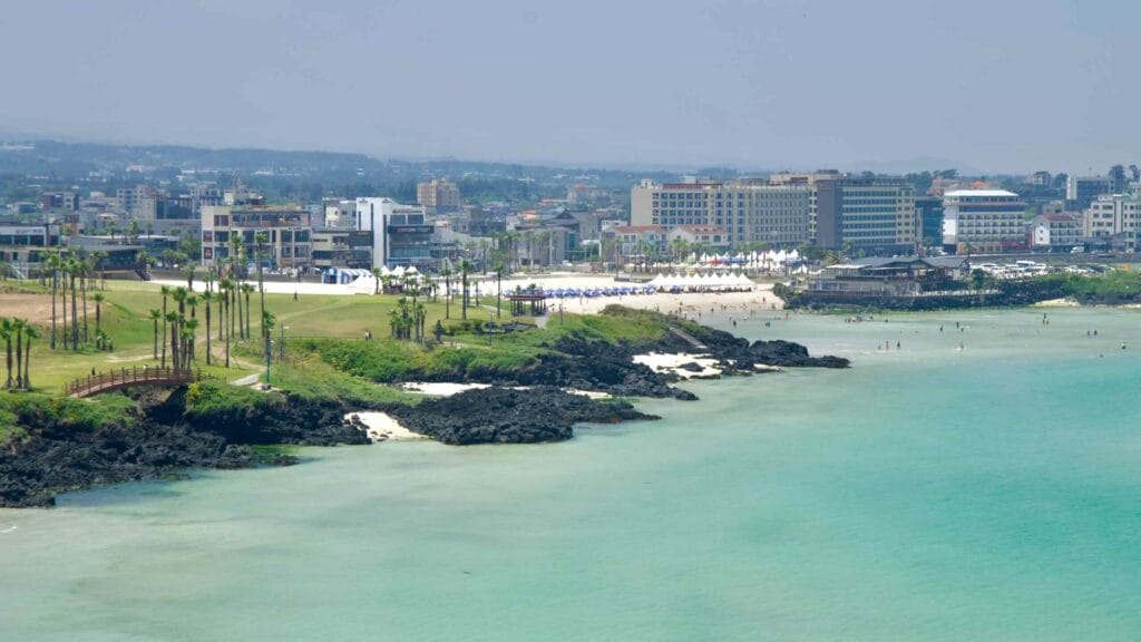 Across the bay, hotels and palms line the sands of Hamdeok.