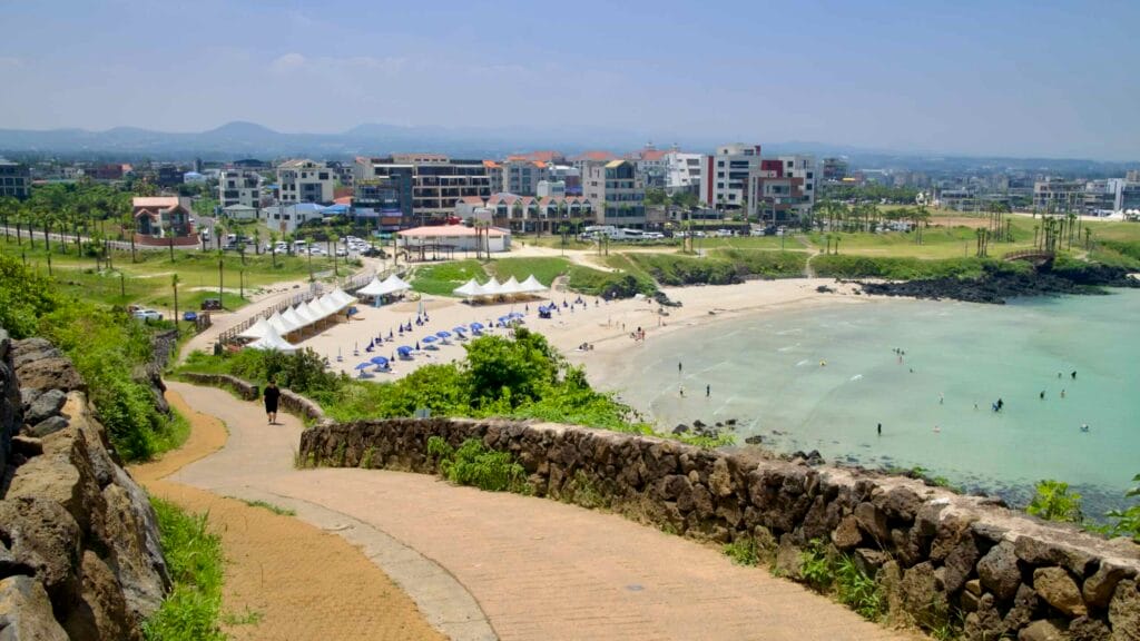A curving stone-walled path descends Seoubong toward Hamdeok Beach.