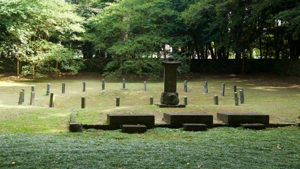 A stone stele and a ring of marker posts stand at sacred Samseonghyeol in a quiet city grove.