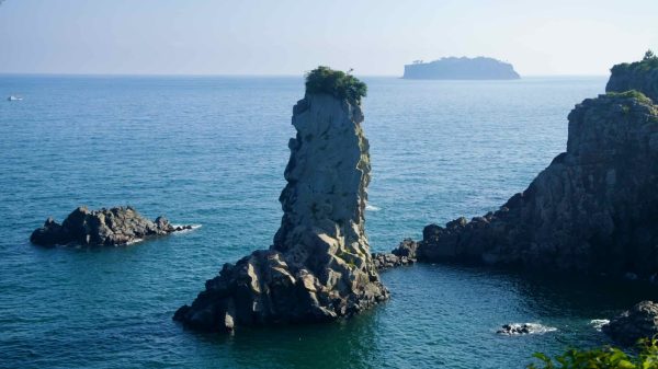 Oedolgae Rock rises sharply from the sea, topped with greenery.