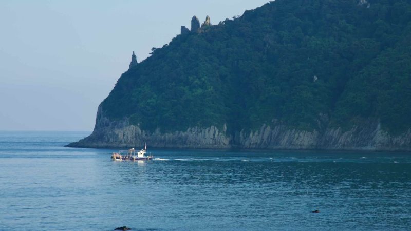 A workboat passes Seopseom Island's pinnacled headland.