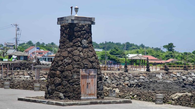 A squat basalt beacon tower stands near the waterfront.