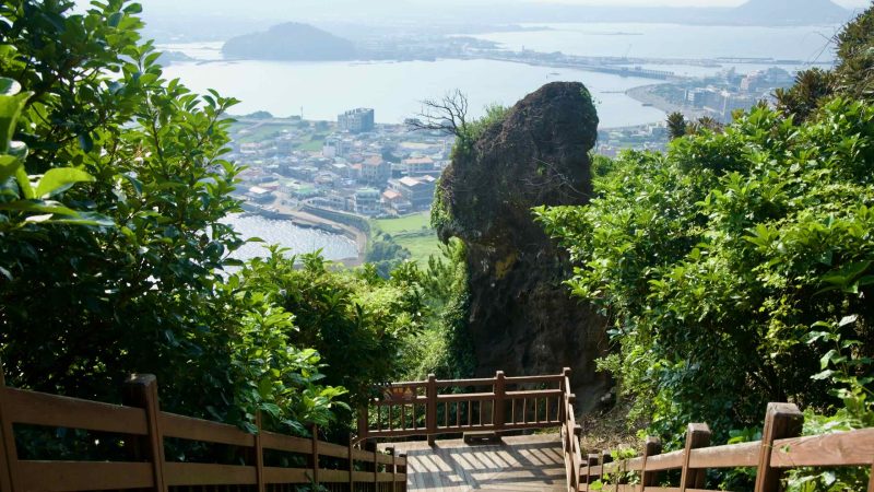 A weathered rock spire rises beside the descending stairs on Seongsan Ilchulbong.