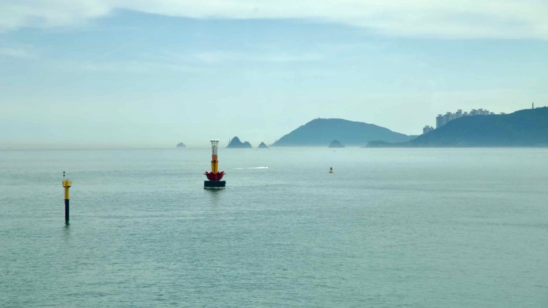 Navigation buoys with distant islets and headlands off the Busan coast.