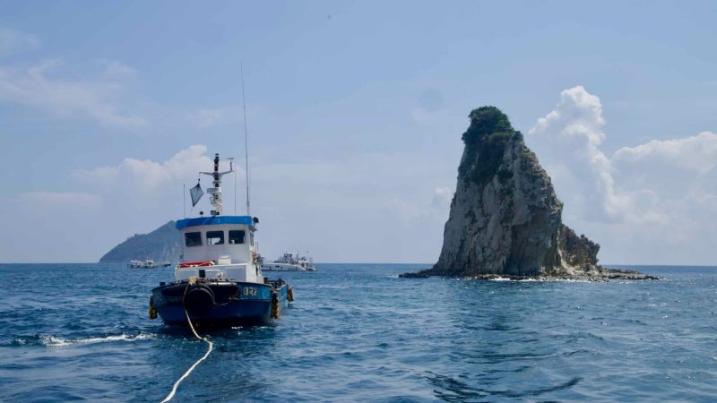 A workboat idles by Munseom’s sea stack off Seogwipo.
