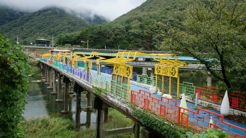 An elevated view shows the Omija Theme Tunnel bridge and colorful panels over the river.