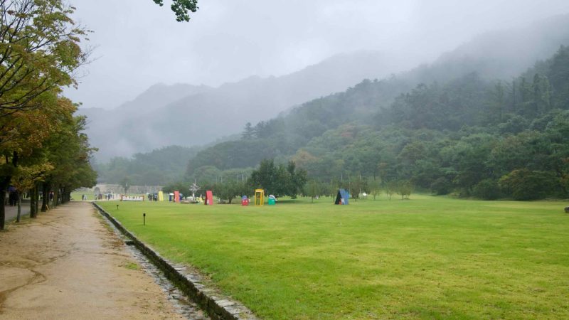 Wide lawns and photo props sit beneath misty mountains in Mungyeong Saejae Provincial Park.
