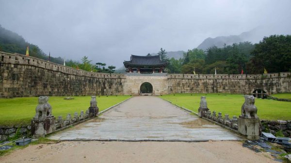 A straight approach leads to the main stone gate and roofed pavilion at Mungyeong Saejae.
