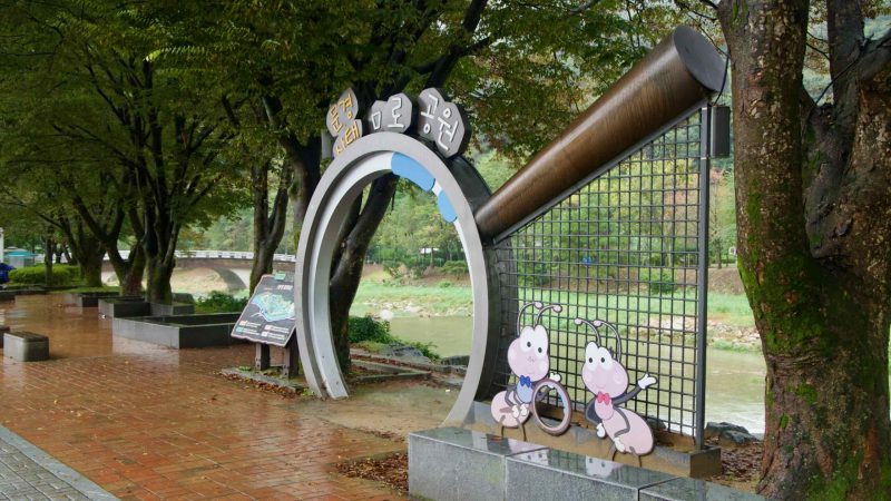 A gateway sign for the Mungyeong Ecological Maze Park stands along the riverside promenade.