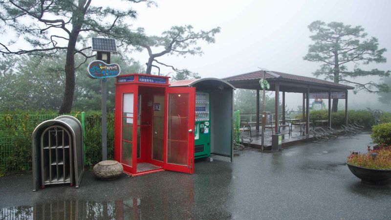 A red certification booth and vending machine serve cyclists at the summit.