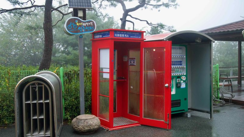 A red kiosk with a stamp stands beside a humming vending machine on the summit.