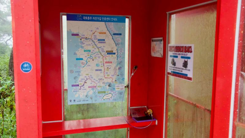 Inside the booth, riders stamp passports beneath a posted route map.