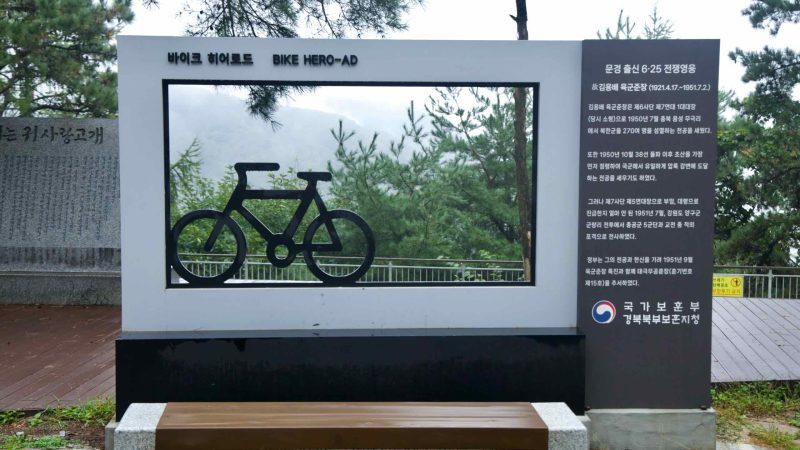 A bike-shaped frame and tribute panel mark a viewpoint near Ihwa Pass.