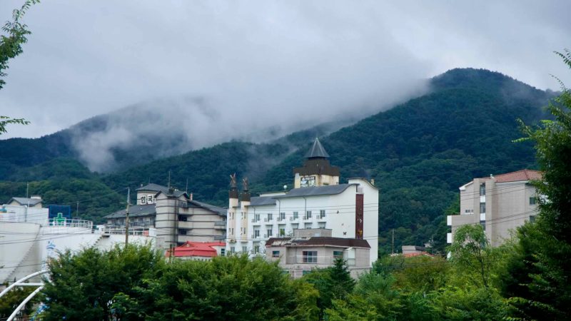Low clouds drift over the ridge above Suanbo’s resort buildings after rain.