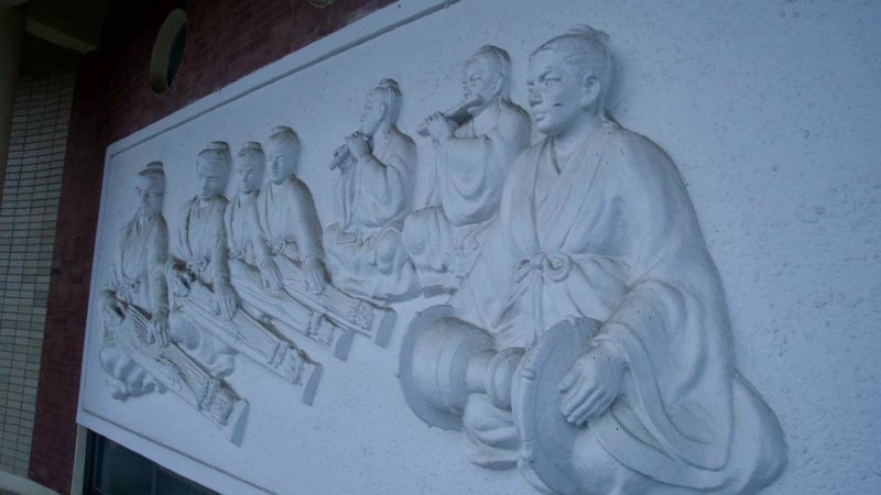 A bas-relief of traditional musicians decorates the cultural hall at {loc}, with figures playing flutes and gayageum.