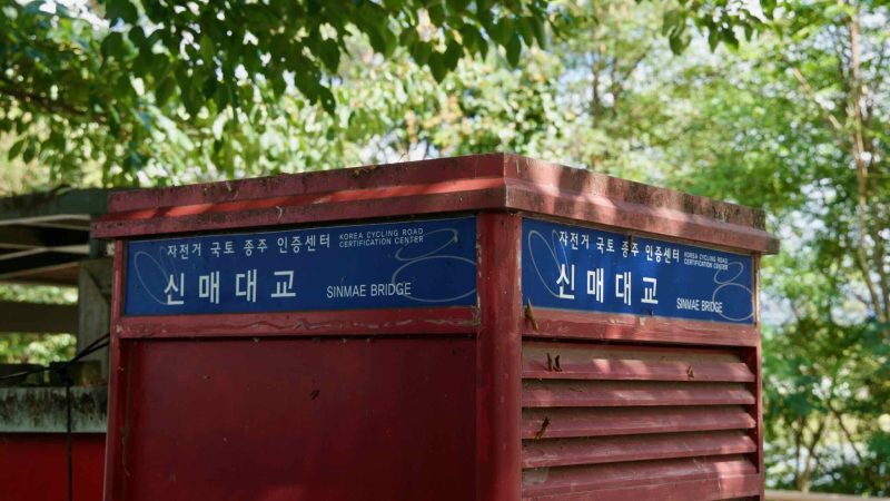 A close view shows the Sinmae Bridge certification booth name panels along the Bukhangang Bike Path.