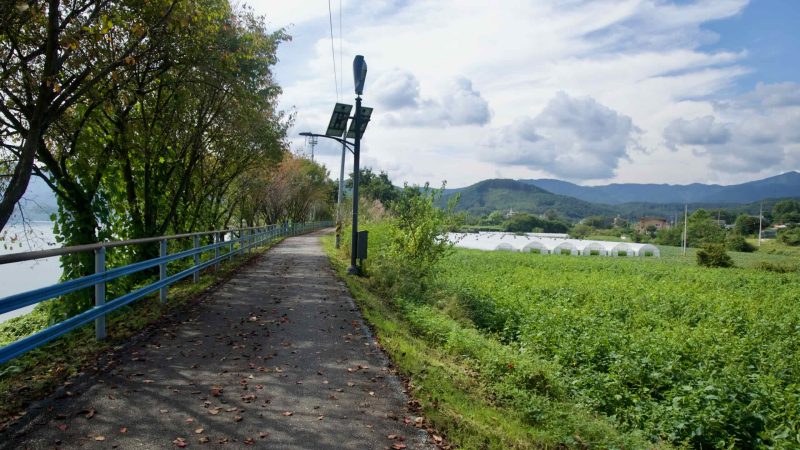 Solar lamps line the bike path past farms and greenhouses above the river.