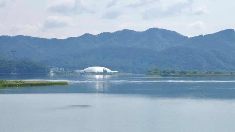 A white domed building sits beyond Uiam Lake with forested hills behind.