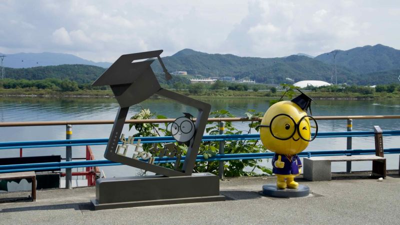 Cartoon mascot sculptures stand beside the lakeside path in Chuncheon.