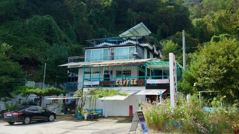 A tiered hillside café with a big COFFEE sign faces the lake below forested slopes.
