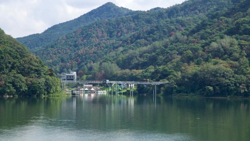 A riverside pier sits below wooded hills near Uiam Dam on Uiam Lake.
