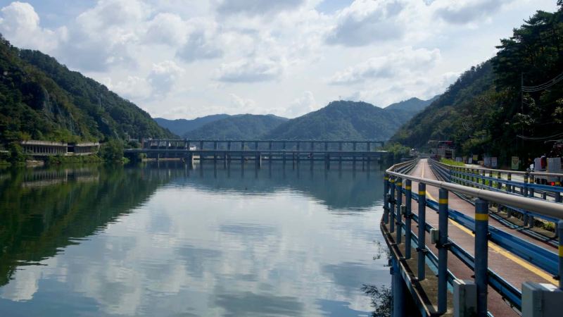 A broad panorama looks across Uiam Lake to Samaksan’s wooded flanks and a string of concrete gallery tunnels along the.