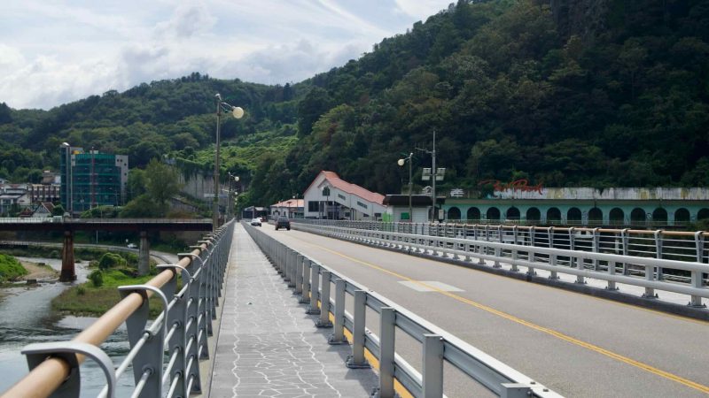 A walkway follows Gangchon Bridge with rails and lamps over the river.