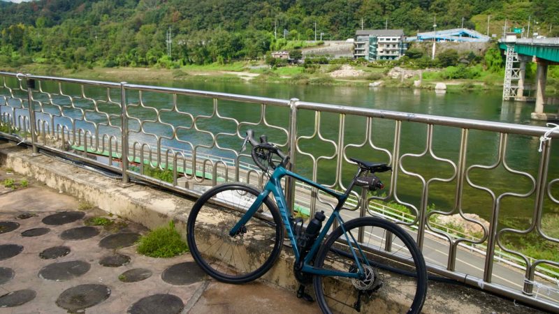 A bicycle leans on a riverside railing above the Bukhangang at Gangchon.