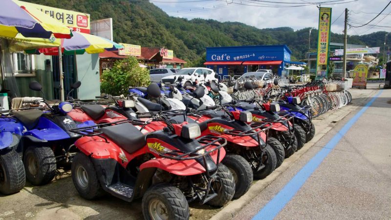 Rows of quad bikes, scooters, and bicycles fill a rental yard on Gangchon’s main strip.
