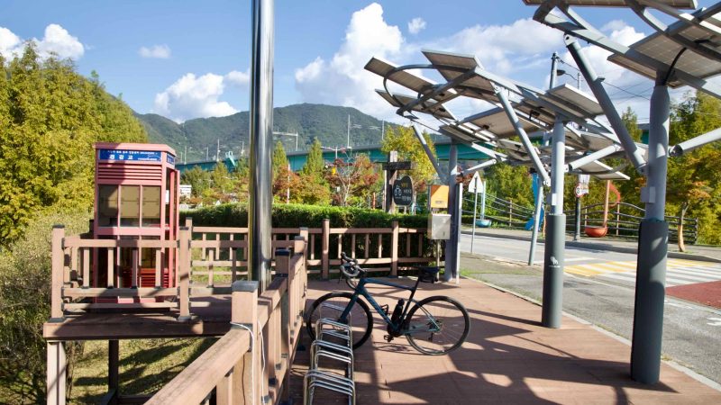 A cycling stop and certification booth sit beside the Gyeongchun Line viaduct in Gapyeong.