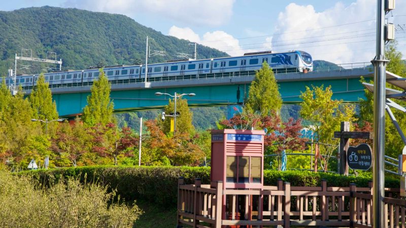 A Gyeongchun Line train crosses the viaduct above the Kyunggang Bridge booth.
