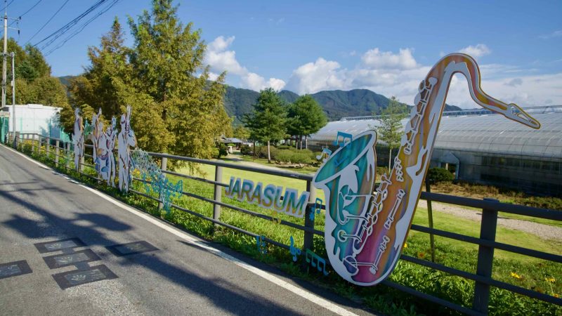Saxophone-themed JARASUM artwork decorates a roadside fence near the park entrance.