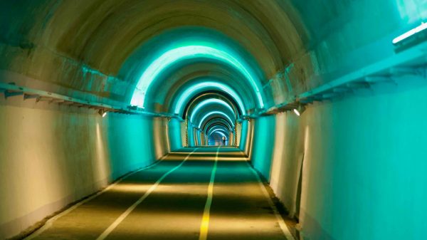 Teal LED arches repeat through Saekhyeon Tunnel, forming a glowing rhythm over the lane.
