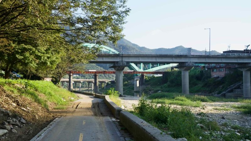 Multiple crossings span the valley at Cheongpyeong: the arched Gyeongchun Line bridge, an older steel truss, and a road viaduct.