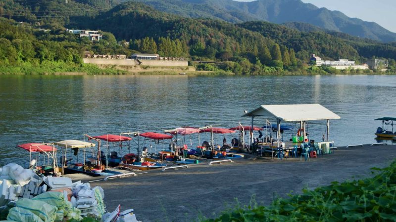 Canopied boats tie up at a North Han River pier in Gapyeong with wooded hills behind.