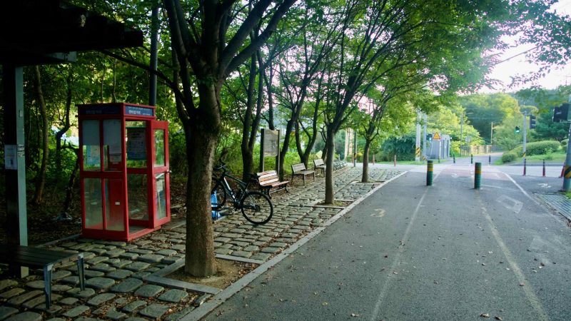 A rest area at Saeteo Samgeori has a red certification booth, benches, and a crossing on the Bukhangang path.