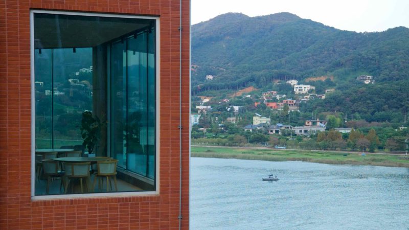 A café window frames the river and hill neighborhoods at Namyangju.