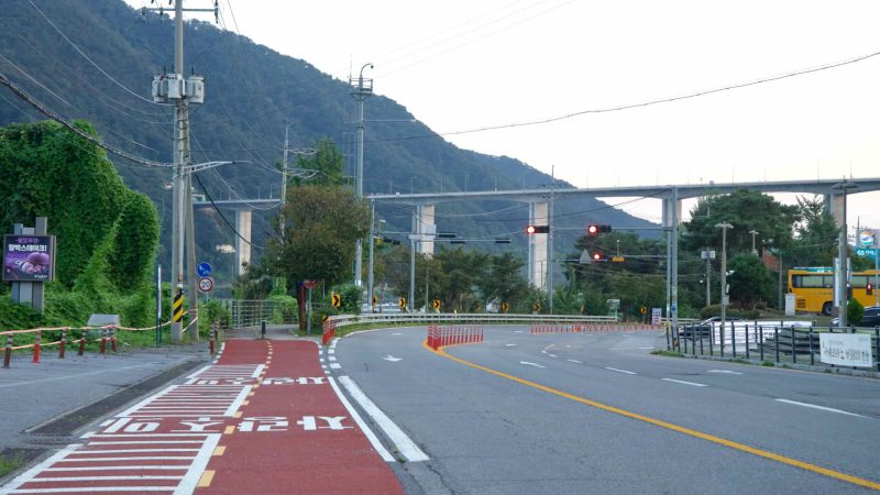 A red bike lane curves toward the river viaduct in Namyangju.