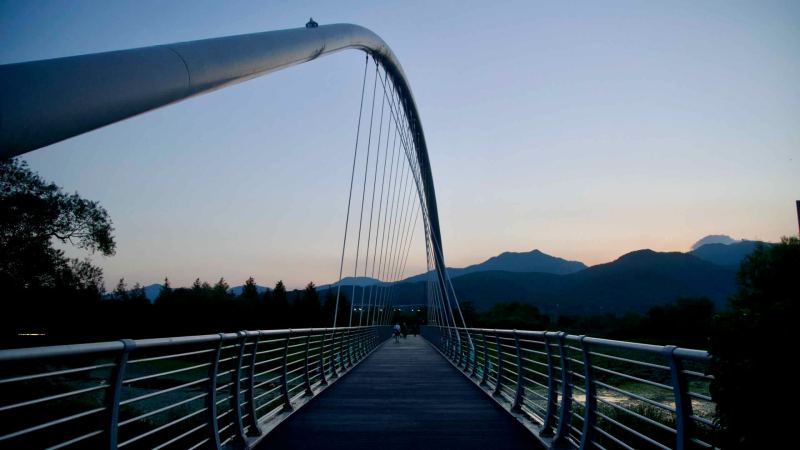 An arch pedestrian bridge crosses the Bukhangang at dusk.