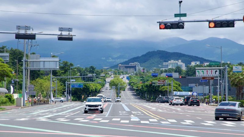 Jeju City boulevard leading toward Hallasan under summer clouds.