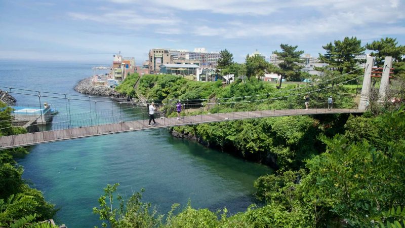 Yongyeon Cloud Bridge above the inlet toward the sea on Jeju’s north coast.