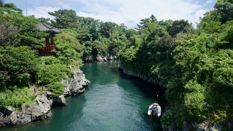 Basalt gorge and pavilion above green water at Yongyeon Valley.